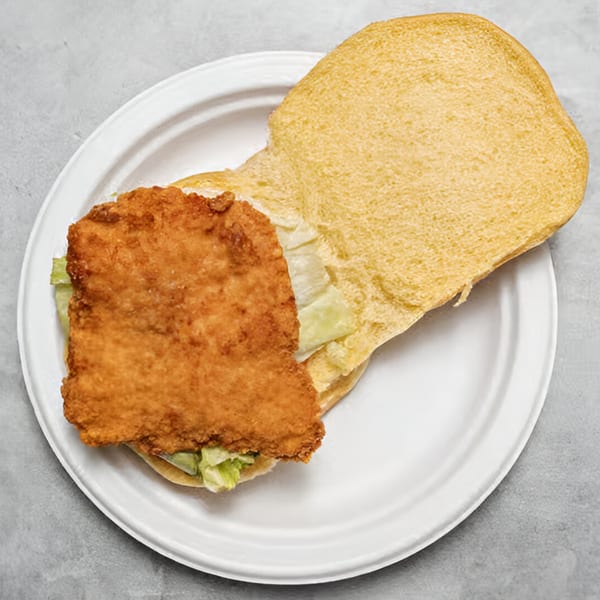 A Chicken Holiday fried chicken sandwich with lettuce on a white plate.