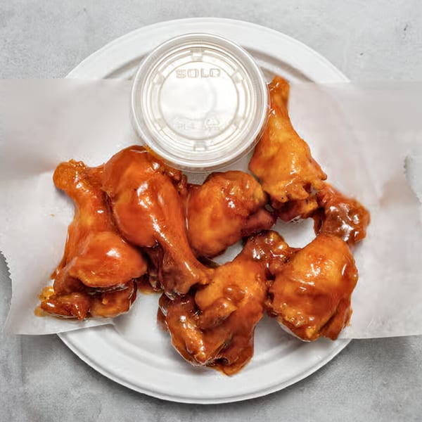 Chicken Holiday Takeout Shop's fried chicken wings with a side of sauce on a white plate.